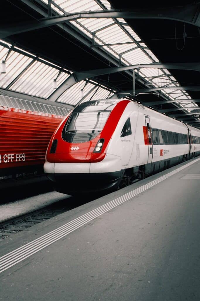 a red and white train traveling through a train station